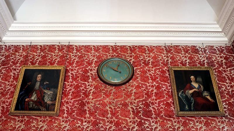 A wall clock with a plain white face and black hands mounted above a closed office door in a quiet hallway