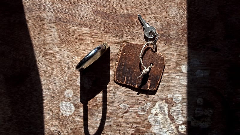 A worn leather wallet lying open on a wooden surface with a folded paper card slotted into one compartment