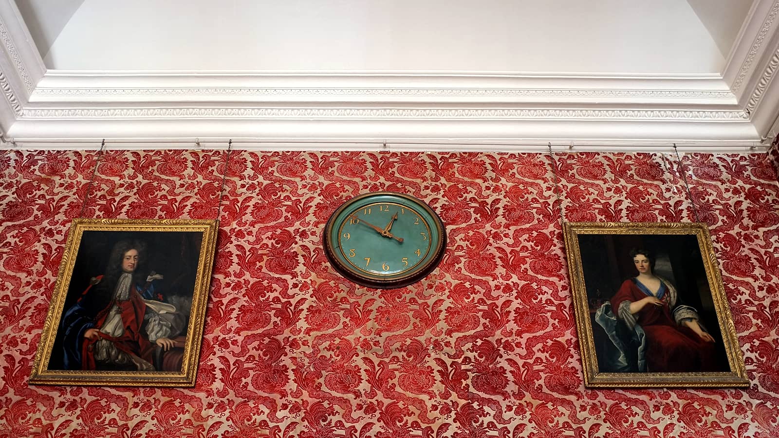 A wall clock with a plain white face and black hands mounted above a closed office door in a quiet hallway