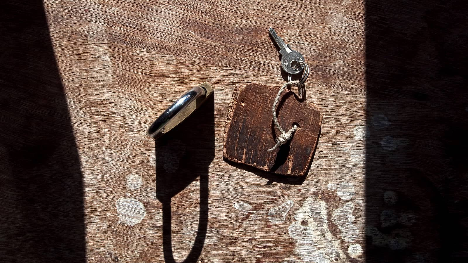 A worn leather wallet lying open on a wooden surface with a folded paper card slotted into one compartment