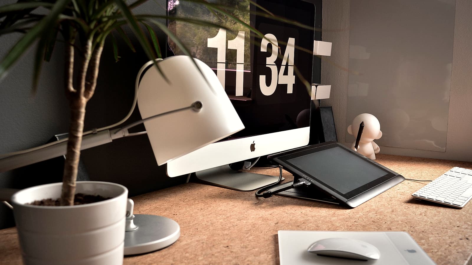 A hand holding a small security key device beside a laptop keyboard on a desk in a quiet office
