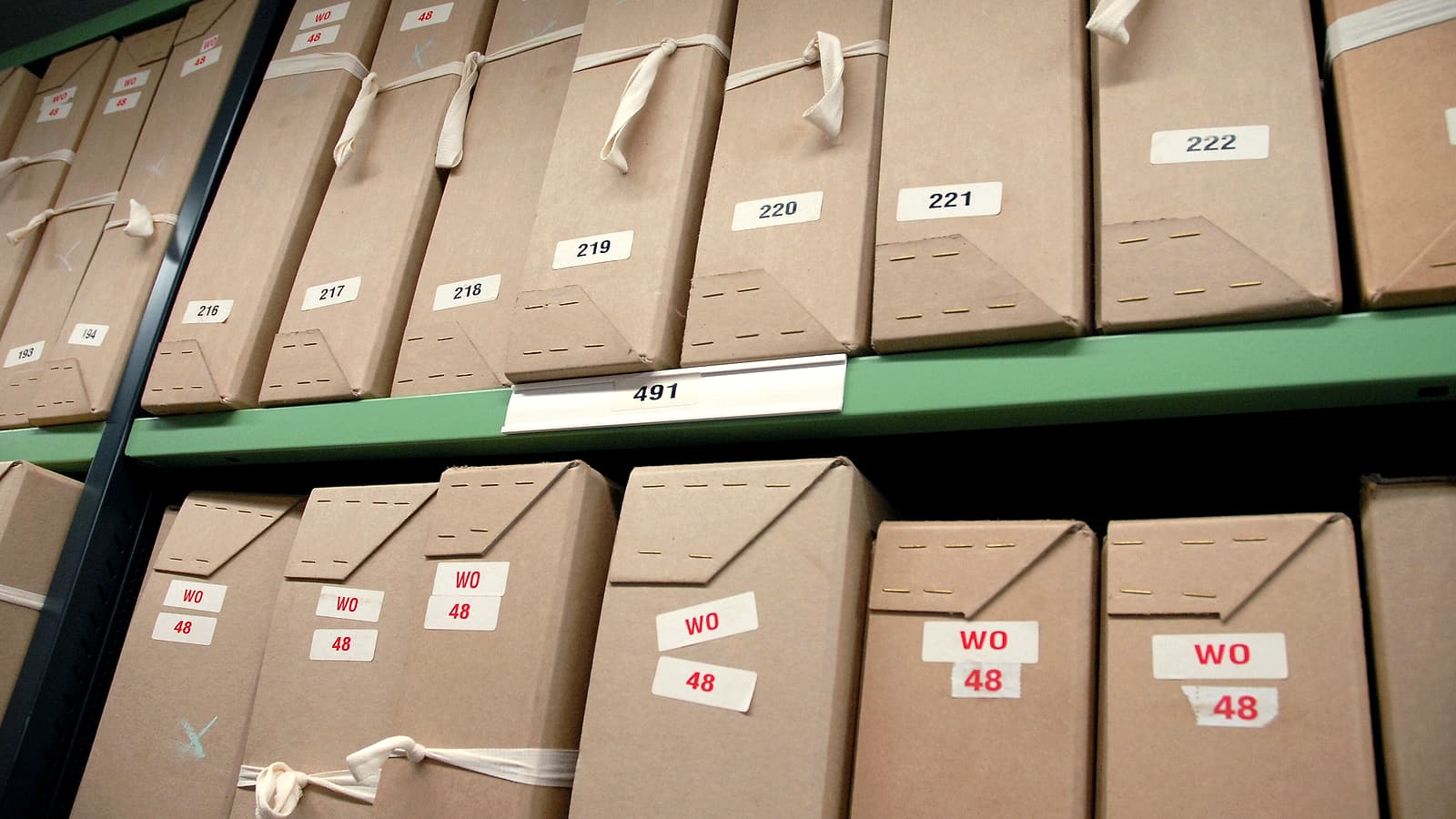 A tall stack of tabbed paper exhibits bound with a large binder clip standing on the corner of a desk